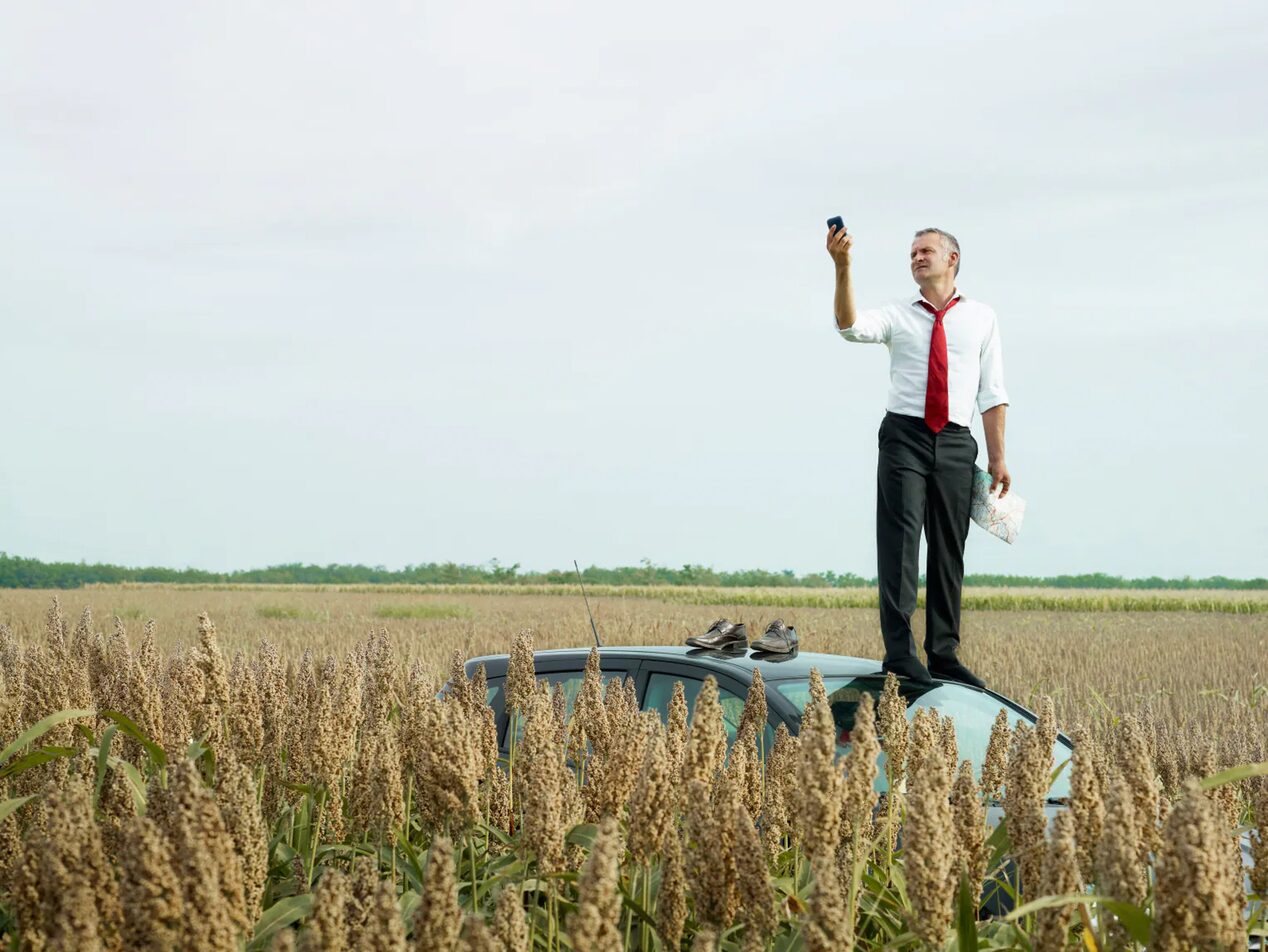 Man Standing on Top of Vehicle Trying to get Service on his Phone